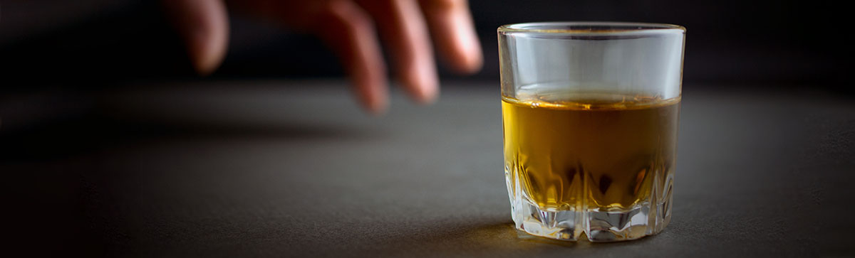 Hand reaching for a glass of alcohol