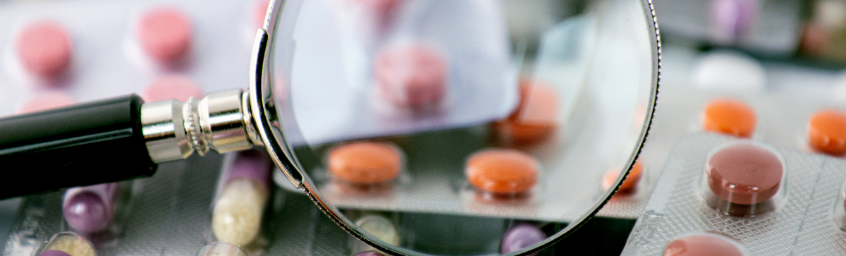 Magnifying glass over pills.