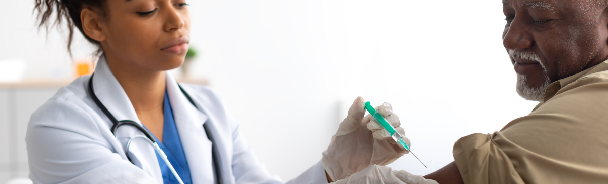 Elderly man receiving a vaccine from a young female care giver.
